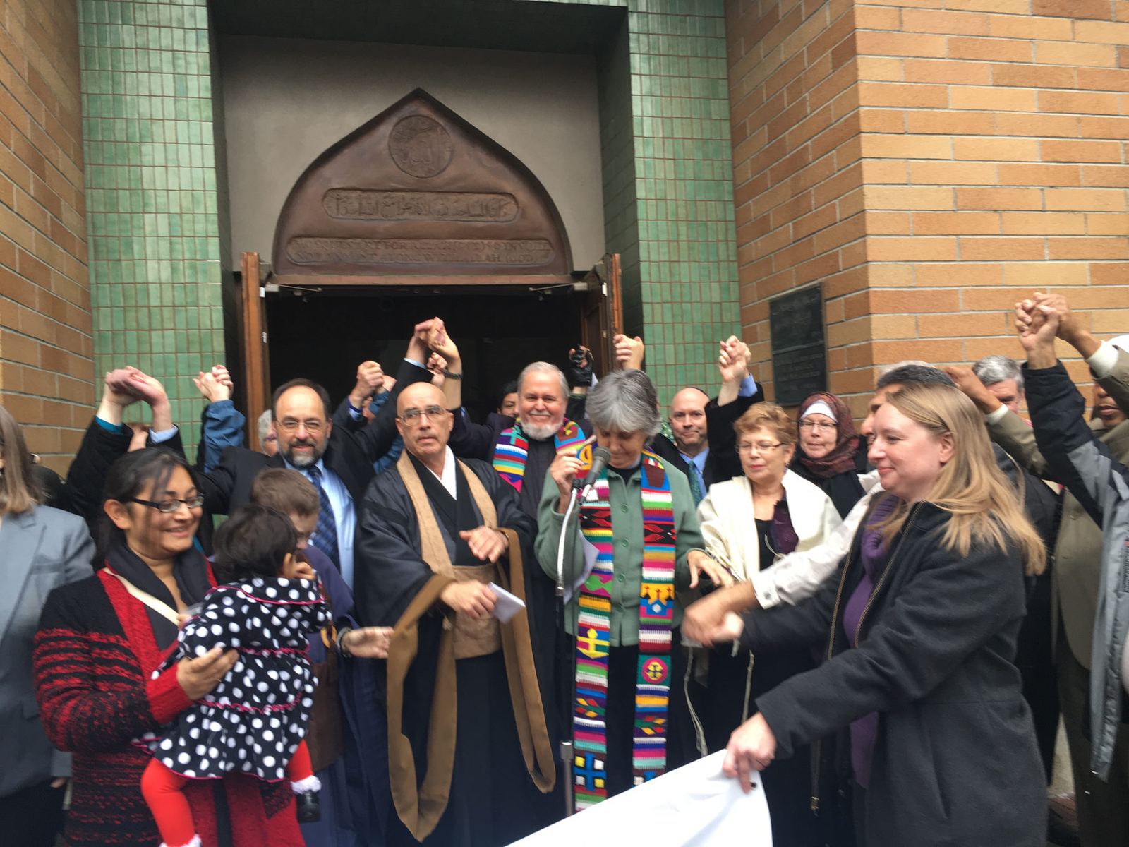 Interfaith visitors and members of the mosque gathered at the green-tiled entrance of Idris Mosque